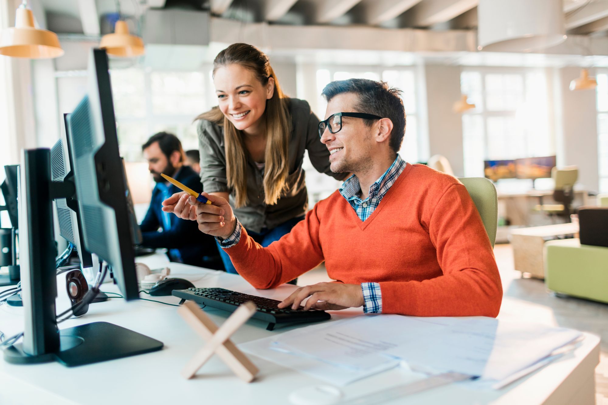 Coworkers collaborating at their desks in modern hot desking setup  