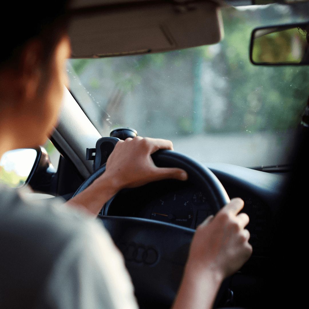 Over-the-shoulder view of a person driving towards a car park.