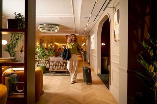 A traveller with a suitcase walking through an airport lounge