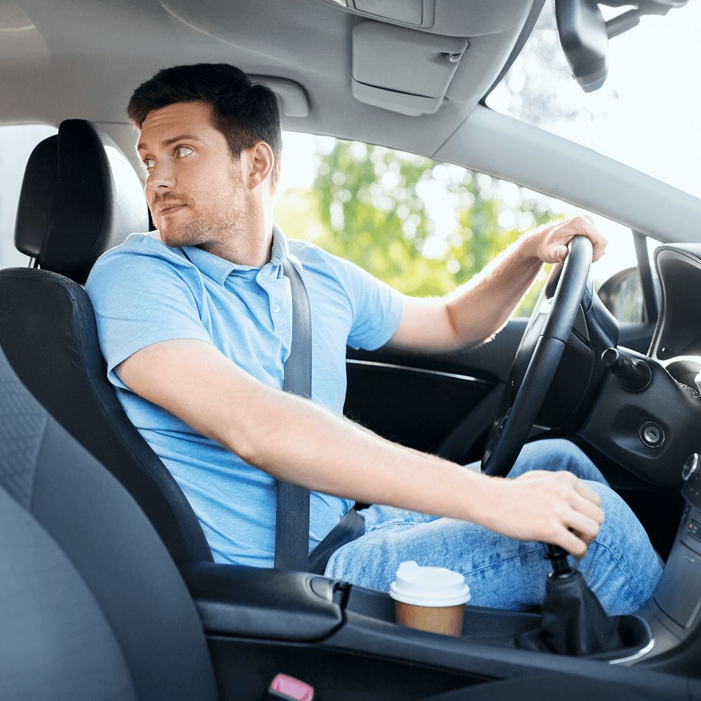 A man driving a car, looking over his shoulder.